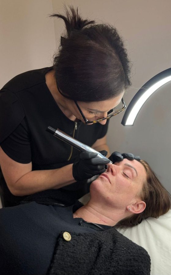 Natalie carrying out a treatment on a client with a handheld device