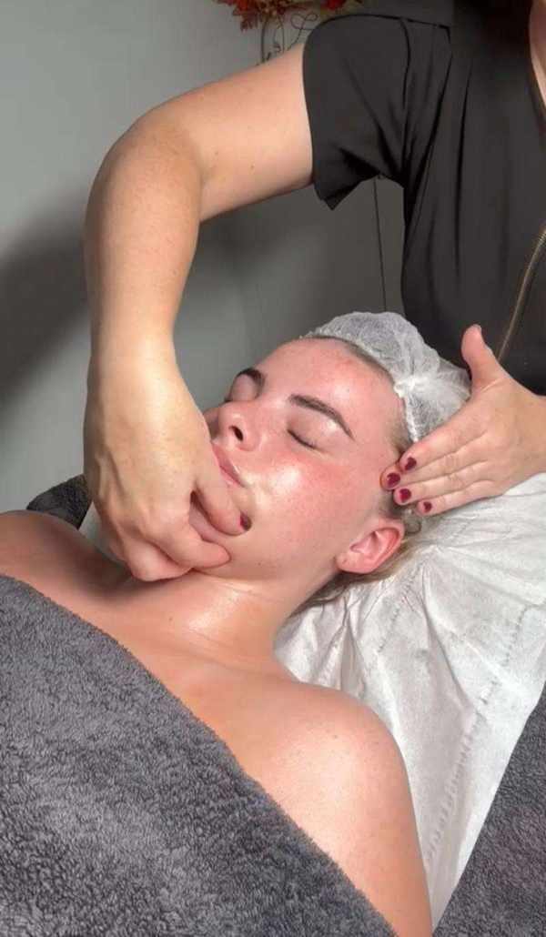 A facial massage being carried out on a client wrapped in towels