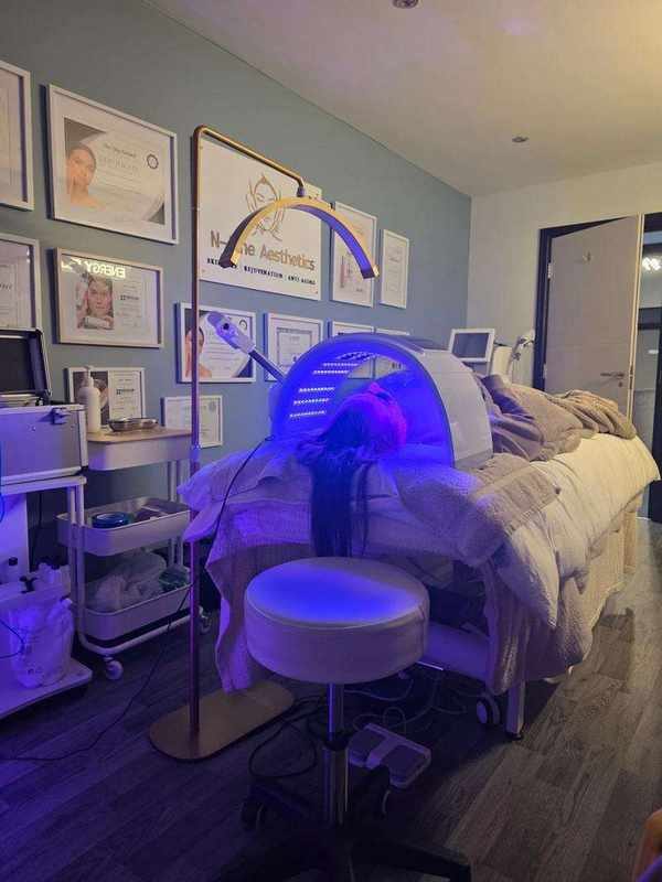 Treatment room with LED light therapy mask, couch and certificates on the wall
